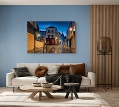 Off the Clock by Sherry Keene, Le Consulat in Montmartre at blue hour, as a large print above a white linen sofa on a dusty blue wall beside oak slat paneling. Shown at 60 x 40 inches. (thumbnail 2)