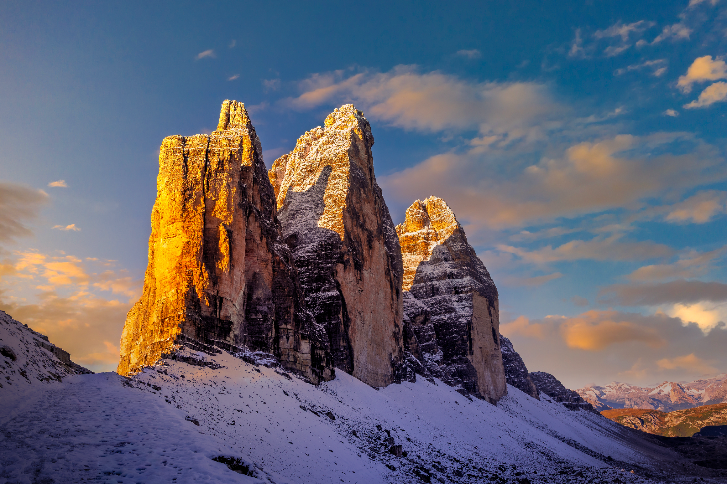 Tre Cime di Lavaredo, also known as Drei Zinnen, glowing in golden morning light after a fresh snowfall in the Dolomites. Fine art photograph by Sherry Keene capturing endurance, solitude, and the split-complement harmony of gold light and violet shadows — a museum-quality collector’s piece from KeeneFine.art