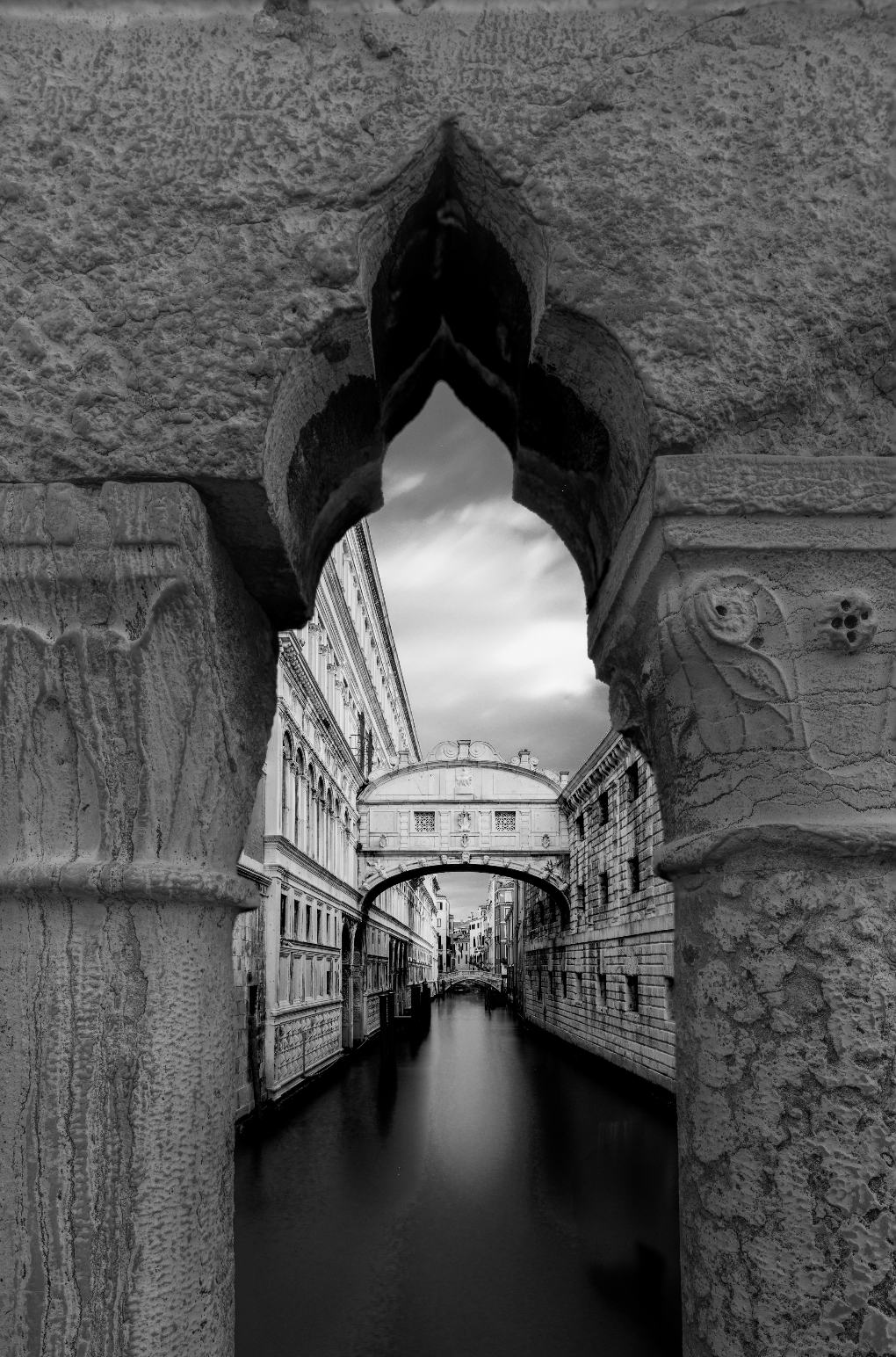 Black and white fine art photograph of the Bridge of Sighs in Venice, captured at dawn through a carved stone archway by photographer Sherry Keene.